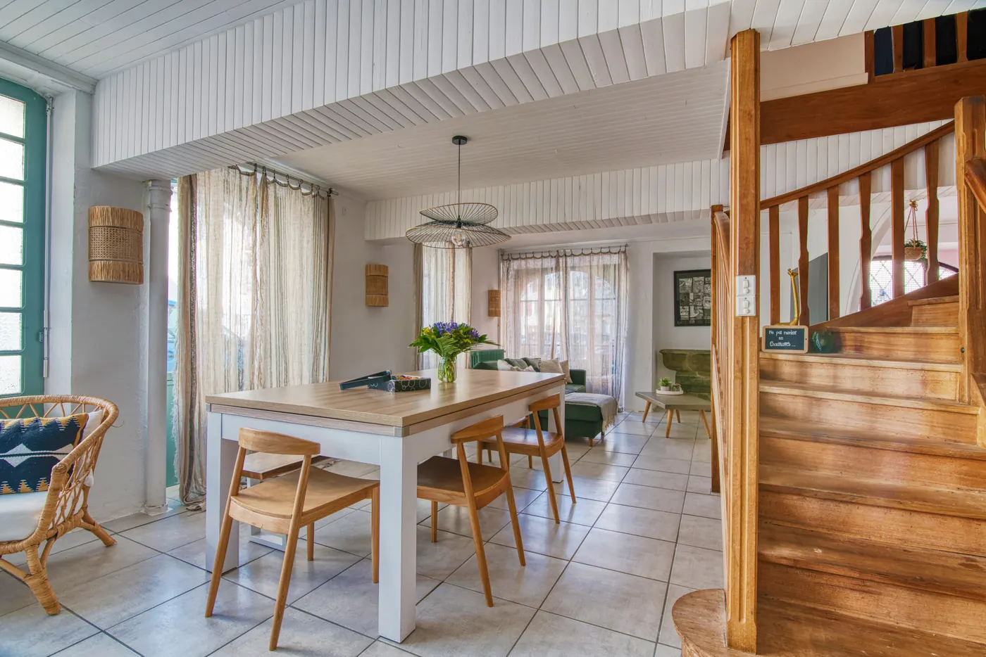 Salle à manger avec escalier en bois et grandes fenêtres