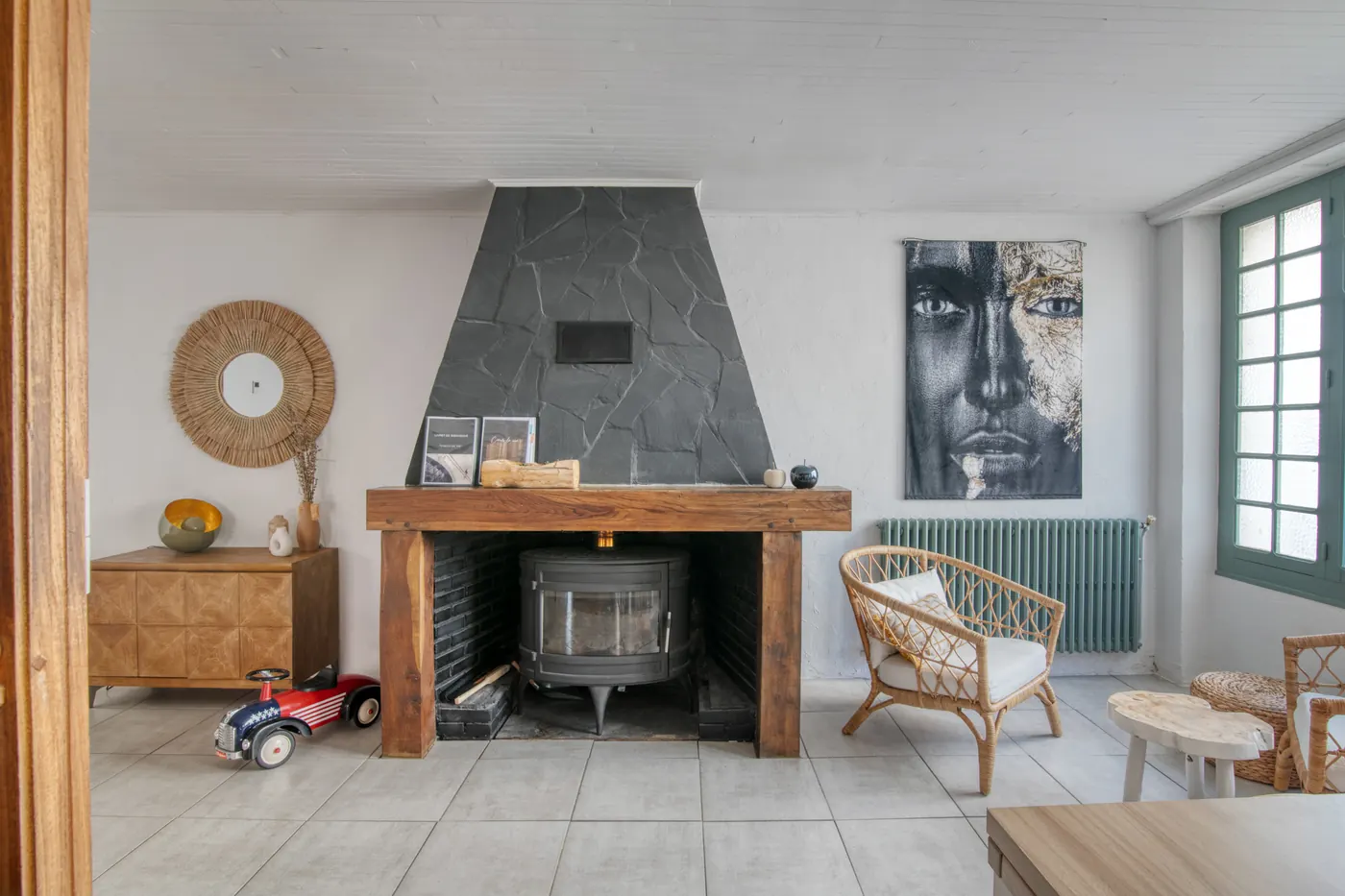 Salon avec poêle à bois et fauteuil en rotin