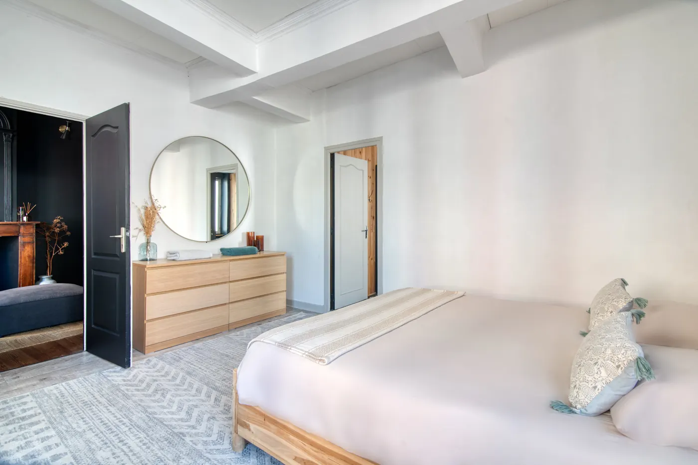 Chambre avec lit king size, commode et miroir rond