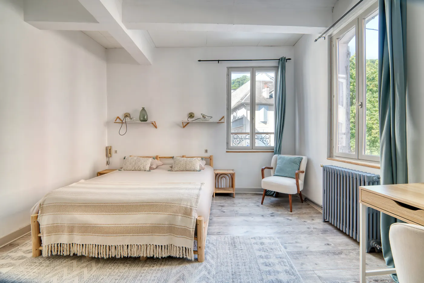 Chambre lumineuse avec grande fenêtre et coin bureau